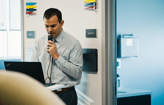 man in office setting using microphone to record into laptop